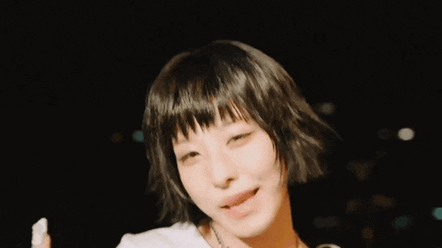 a woman with short hair is wearing a white shirt and a necklace .