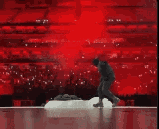 a man is standing on a snow covered stage in front of a red background .