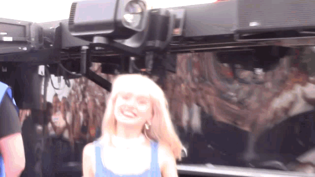 a woman in a blue tank top is smiling in front of a black truck
