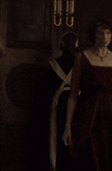 a woman in a red dress stands in a dark room