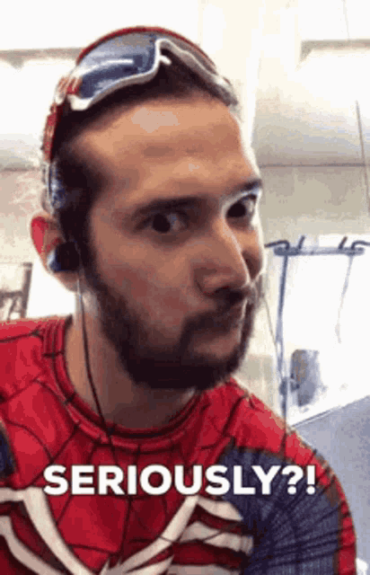 a man in a spiderman costume is wearing sunglasses and headphones and says seriously .