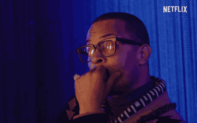 a man wearing glasses and a sweater with a netflix logo on the bottom
