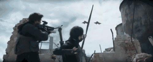 a man is holding a gun and a woman is holding a stick in front of a building .