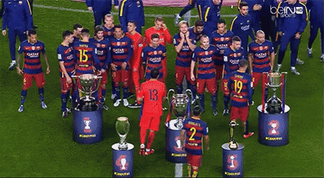 a group of soccer players wearing qatar jerseys stand in front of trophies on a field