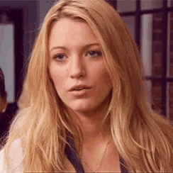 a close up of a woman 's face with long blonde hair and a necklace .