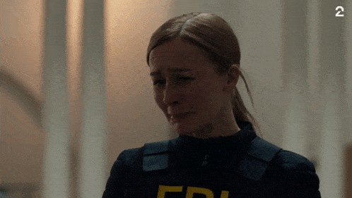 a woman in a fbi uniform is crying in a dark room