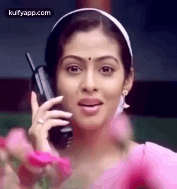 a woman is talking on a cell phone while wearing a pink dress .
