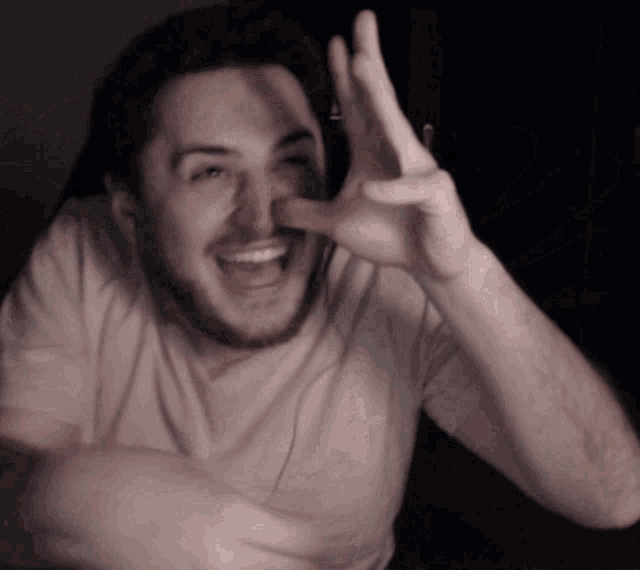 a man in a white shirt is smiling and making a peace sign with his hands