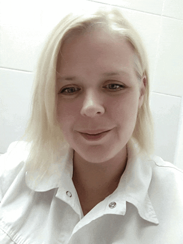a woman with blonde hair is wearing a white shirt and smiling for the camera