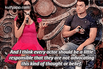 a man and a woman are sitting next to each other and the woman is talking into a microphone .