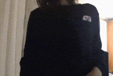 a woman is wearing a black shirt with a cat on the pocket