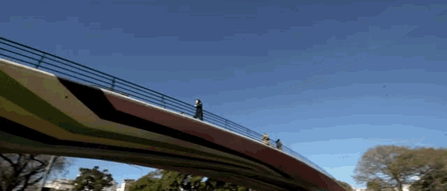 people walking on a bridge with a blue sky behind them
