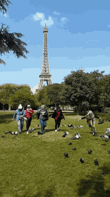 a group of people running in a park with the eiffel tower behind them