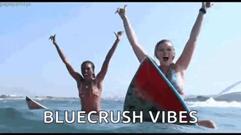 two women are riding a surfboard in the ocean .