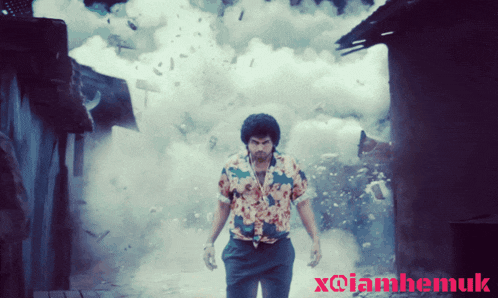 a man in a hawaiian shirt is standing in front of an explosion with x@iamhemuk written on the bottom