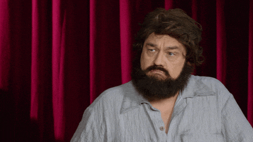 a man with a beard is standing in front of a pink curtain
