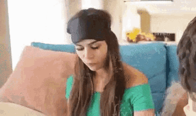 a woman wearing a sleep mask is sitting on a couch with a man .