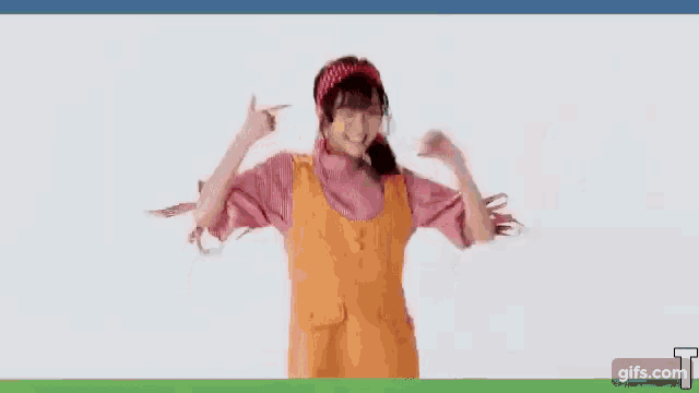 a girl in a pink shirt and orange apron is dancing .