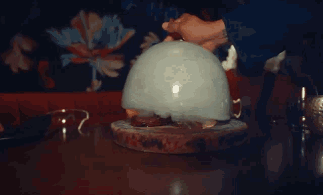 a person is holding a balloon with smoke coming out of it on a table