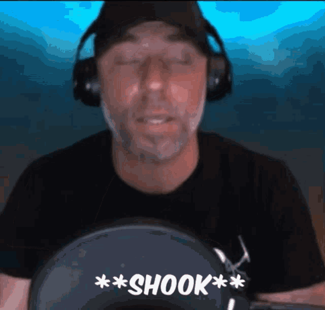 a man wearing headphones and a black shirt with the words shook on it
