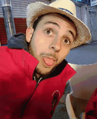 a man wearing a straw hat and a red jacket making a funny face