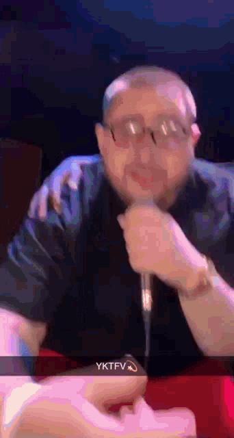 a man wearing glasses is holding a microphone in front of his face ..