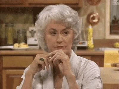 an older woman with gray hair is sitting at a table in a kitchen .