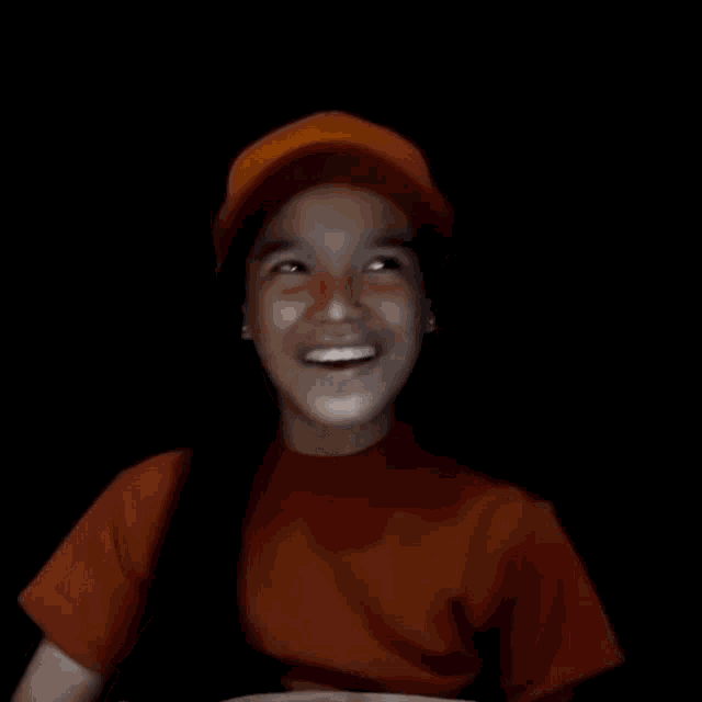 a blurry picture of a person wearing a red shirt and an orange hat .