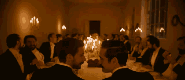 a group of men sitting at a table with candles