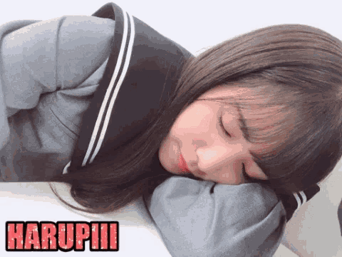 a girl in a school uniform is laying down with her head on her pillow and the word harupuu written in red