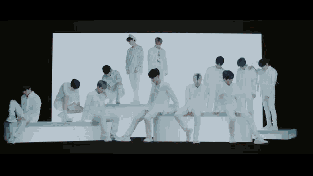 a group of men are standing and sitting in front of a large screen
