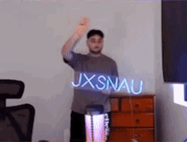 a man is standing in a room with a sign that says jxsnau on it .