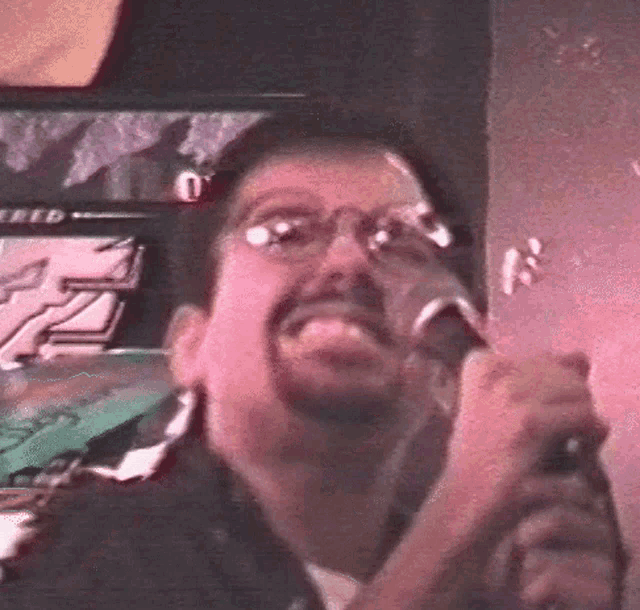a man with glasses is holding a microphone in front of a sign that says speed on it
