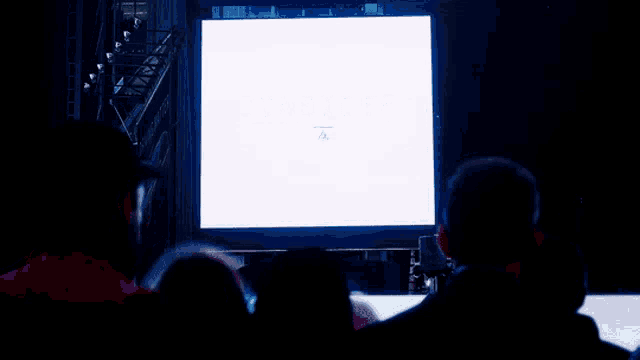 people watching a large screen with the word consider on it