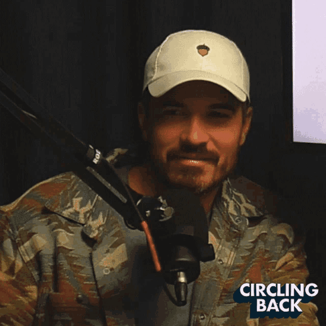 a man wearing a hat stands in front of a microphone with the words circling back on the bottom