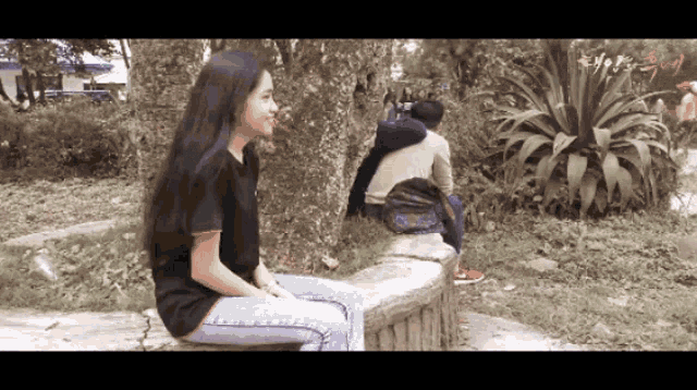 a girl sits on a bench in a park while a man sits on a tree branch