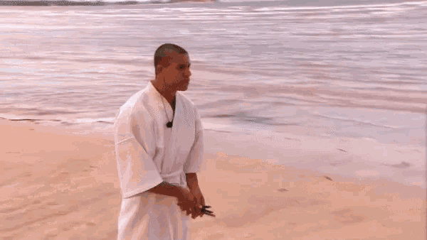 a man and a woman are standing on a sandy beach talking to each other .