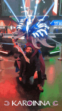 a man with a beard is kneeling next to a large costume with the word karoinna c on the bottom