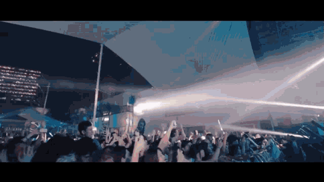 a crowd of people are gathered under a white canopy at a concert