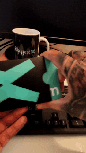a mug that says blizzard on it sits next to a keyboard