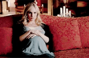 a pregnant woman is sitting on a red couch with red pillows holding her belly .