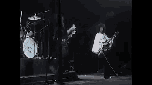 a group of people are playing instruments on a stage and singing into microphones .