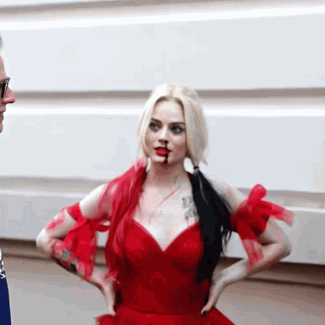 a woman in a red dress with blood on her face is standing in front of a man .
