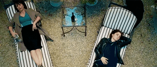 two women are laying in striped chairs on the ground .