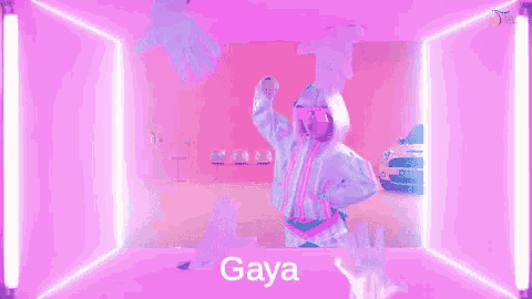 a woman is dancing in a pink room with neon lights and the word gaya is on the screen .