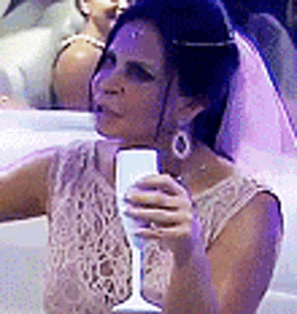 a woman in a wedding dress is holding a glass of wine and taking a selfie .