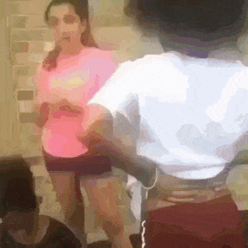 a woman in a pink shirt and shorts is standing next to a man in a white shirt .