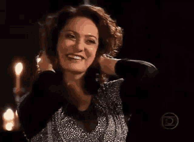 a woman is smiling and looking at the camera while holding her hair .