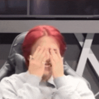 a person with red hair is covering their face with their hands .