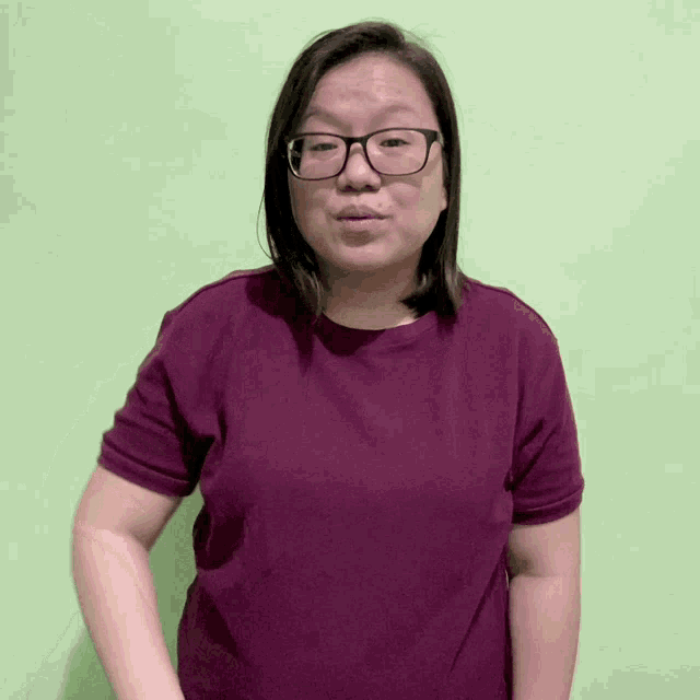 a woman wearing glasses and a purple shirt is smiling